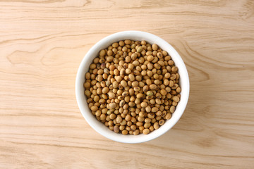 Soybeans in a white bowl on a wooden floor.