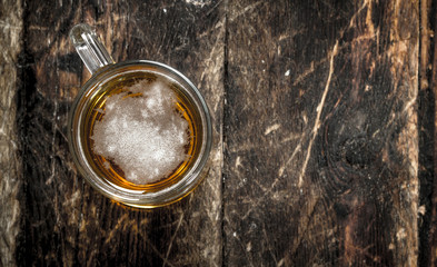 glass of fresh beer. On wooden background.