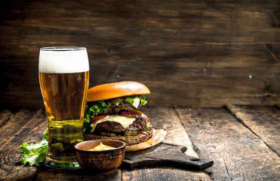 Fast food. A big burger with beef and a glass of beer.