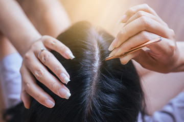 Woman plucking gray hair with tweezers