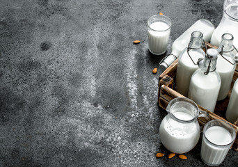 Fresh milk in bottles and jugs with a wooden box.