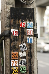motorbike taxi number tags hanging on a pole in a busy city street