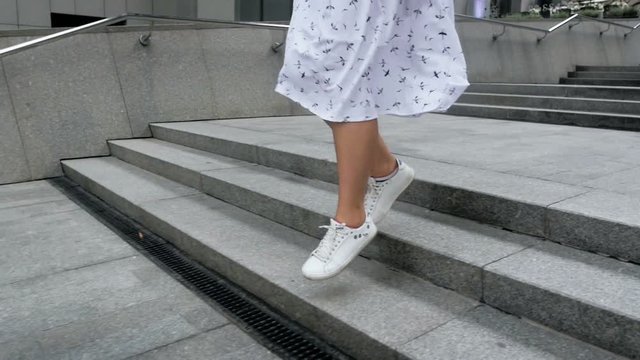 Slow motion video of happy young woman skipping and running down stone stairs