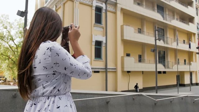 Slow motion video of stylish young woman making photographs with old camera