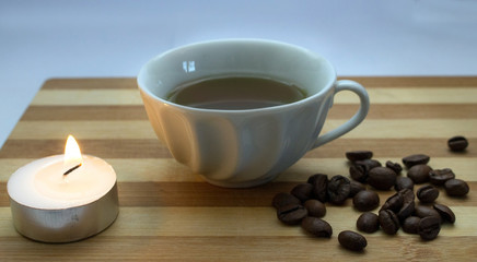 Obraz na płótnie Canvas a cup of coffee, coffee beans, a lighted candle