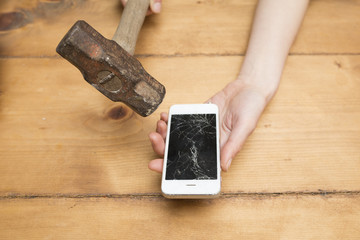 画面のひび割れたスマートフォンとハンマー
