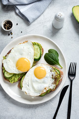 Fried egg, avocado and cucumber on whole grain toasted bread . Healthy eating, healthy breakfast food concept
