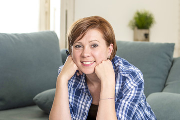 Fototapeta premium young attractive and happy red hair woman around 30 years old smiling confident at home living room holding pen in her hand looking relaxed