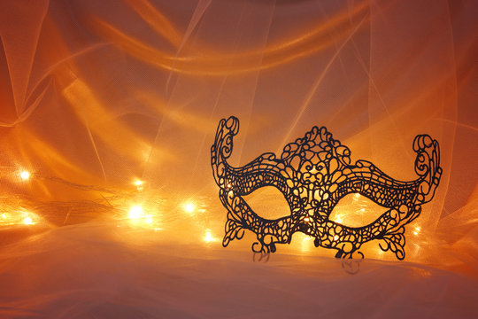 Image of black elegant lace venetian mask over tulle background.
