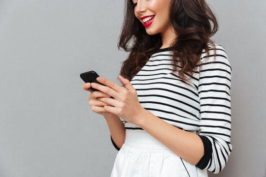 Cropped image of a smiling girl using mobile phone