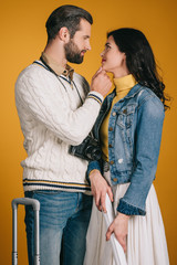 attractive couple looking at each other isolated on yellow