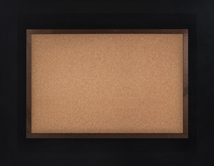 Fototapeta premium Empty corkboard (cork board) in frame on black wall