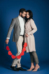 couple holding garland of red hearts and hugging on blue