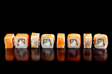 Appetite set of sushi rolls assorted on a black background close-up.