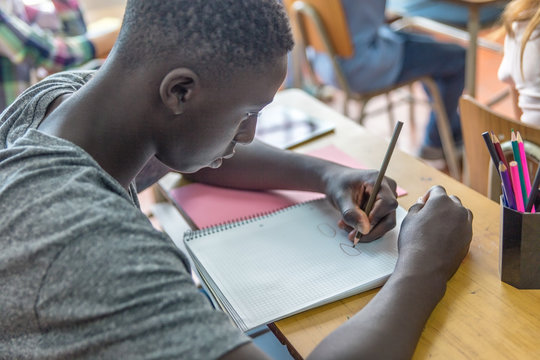 African male teenager making lesson in the classroom and worried about the test