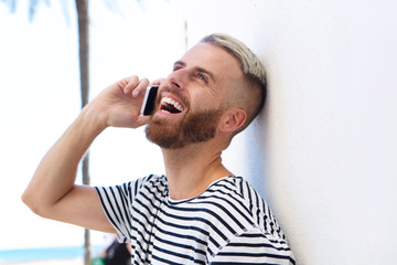 cool young guy laughing and talking on cell phone