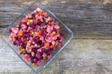 Vinaigrette of beets, potatoes, pickles, onions, carrots, green peas, herbs and seasonings. Space for copy space on a wooden background.