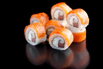 Original set of sushi with salmon, tuna and Philadelphia cheese on a black background close-up.