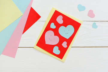 Valentines day or Mothers day greeting card with pink and blue hearts. Scissors, glue stick, colored paper sheets set on a wooden table. Fun art and craft with paper for children. Top view 