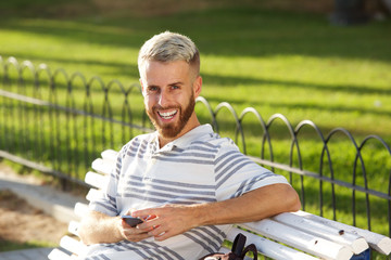 happy man sitting in park with cellphone