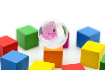 Obraz premium mini glass globe close up with colourful wood block using as background.