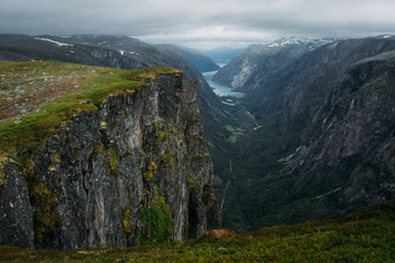 Fototapeta premium view of rocks and grassy cliff, mountain river on background, Norway, Hardangervidda National Park