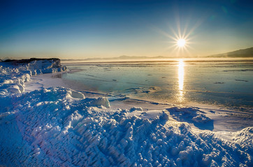 Ice floes floating on the fog water in the lake Baikal and hill. Sunset