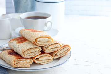 Homemade pancakes stuffed, wrapped with an envelope on a white plate, traditional food on a pancake week, horizontal, copy space