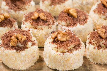 a lot of cakes lined on a wooden table, dessert with walnuts