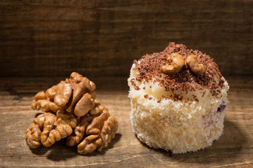 cake on a wooden table, dessert decorated with walnut, walnut nearby, rustic style