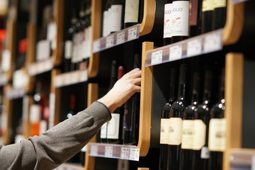 Auswahl einer Flasche Wein im Supermarkt