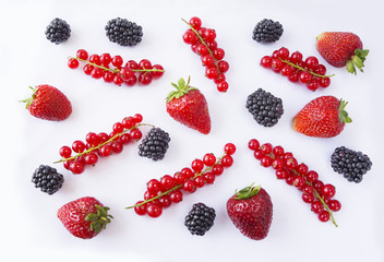 Background of black and red food. Ripe red currants, strawberries and blackberries on a white background. Mixed berries with copy space for text. Black and red berries. 