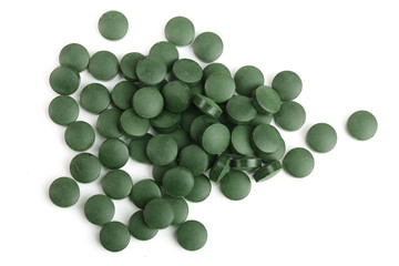 heap of Spirulina tablets algae nutritional supplement isolated on white background close up top view. Flat lay