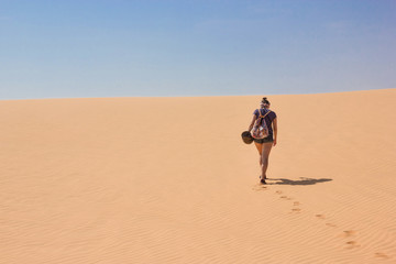 Fototapeta na wymiar back view of lonely woman with backpack walking in desert, Vietnam, Phan Thiet