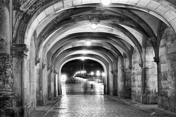 Fototapeta na wymiar Shadows of people walking at night under ancient medieval loggias