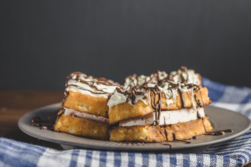 waffles with cream and chocolate on plate on wooden table, free space for text.