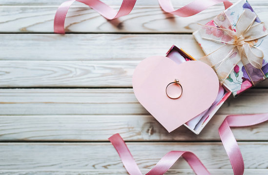 Marriage proposal concept. A wedding ring in a gift box on a wooden background. Valentine's Day. Copy space.