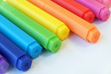 Colorful pens arranged creatively on white background