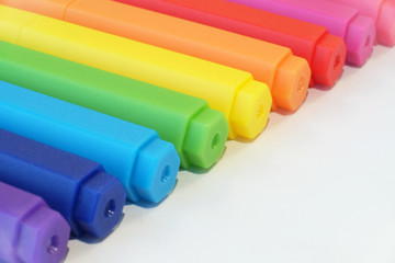 Colorful pens arranged in row on white background