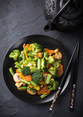 Hot stir fried vegetables on black plate. Healthy asian food concept with copy space. © Iryna Melnyk