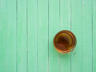 A glass cup of black tea on a mint-colored wooden table