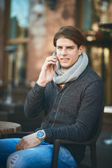 Man using smart phone and drinking coffee while sitting at cafe.