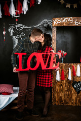 Young cheerful european couple in love embracing and kissing, in decorated with hearts studio on valentine day, dating.