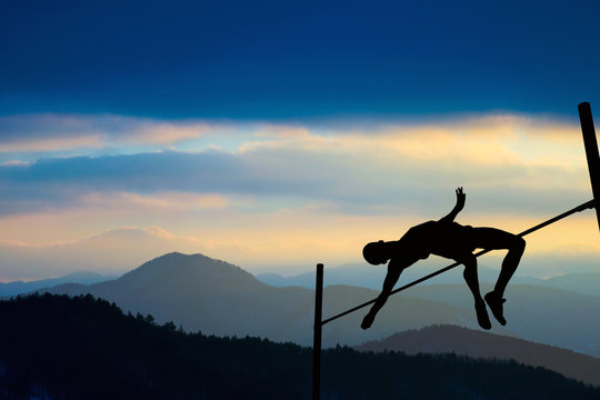 Silhouette of athlete competing in pole vault at dusk