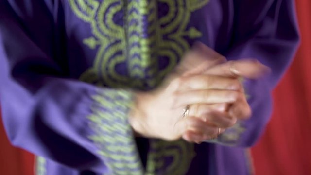 Closeup of woman wearing blue djellaba and rings clapping rhythmically.