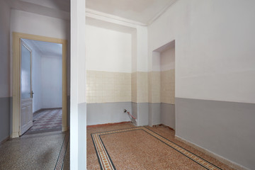 Empty apartment interior with kitchen area, corridor with room and tiled floor