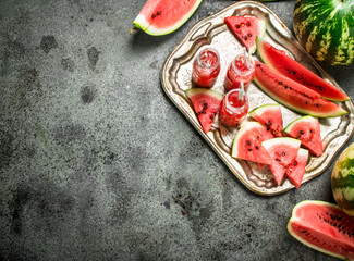 Watermelon juice in bottles on a steel tray.