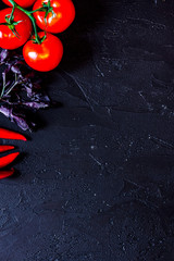 Cook workplace. Tomato, peper, basil on black table background t
