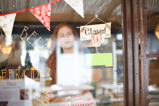 Small business owner in cafe turning closed sign