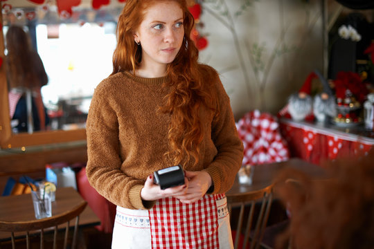 Waitress in cafe holding credit card reader